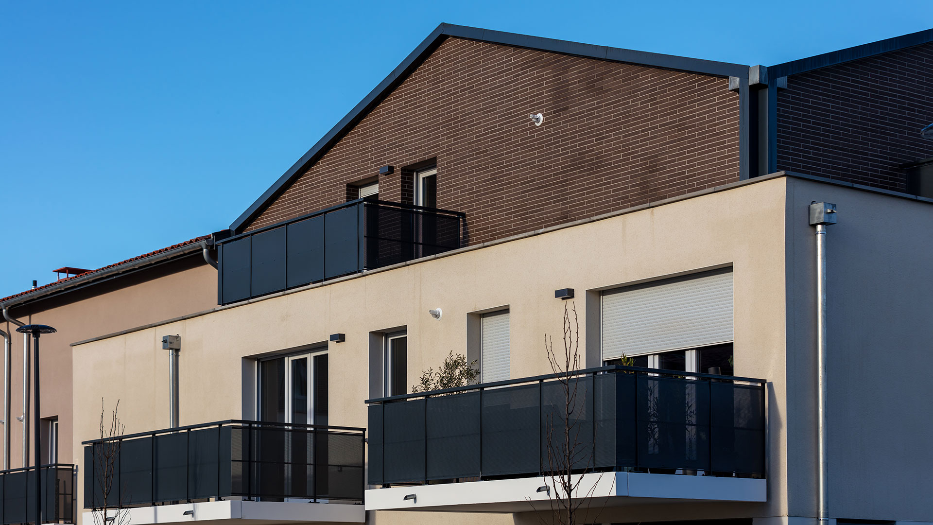 Façade de la résidence L’Écrin Rose présentant une diversité de matériaux et couleurs : enduit de teinte chaude ou claire, parement en plaquettes.